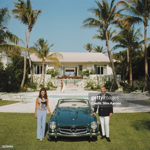 Alvin and Lilly Fuller outside their new home in Palm Beach, Florida, pose with their fashionable European sports car, the Mercedes 190SL.