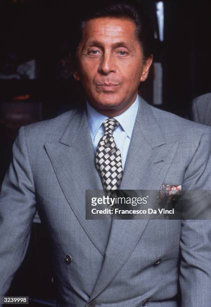Italian fashion designer Valentino wearing a grey double-breasted suit jacket and patterned tie.