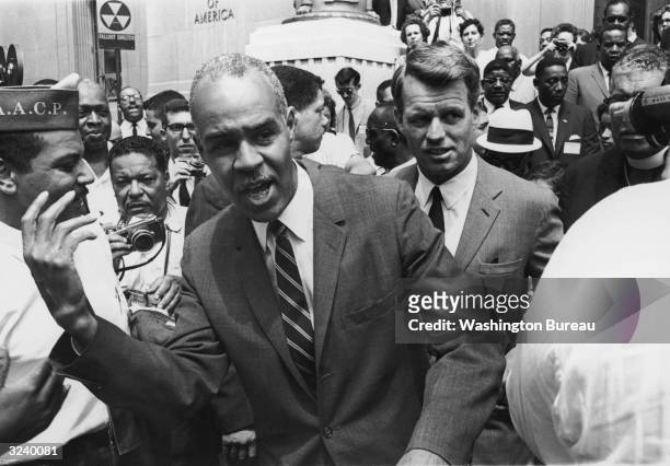 Executive secretary Roy Wilkins walks in front of U.S. Attorney general Robert Kennedy during a NAACP march in front of the Justice Building in...