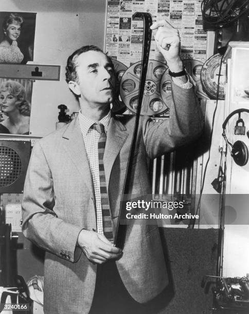 Italian director Michelangelo Antonioni looks at a strip of film in a film lab.