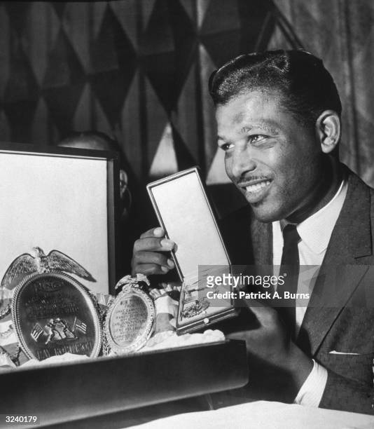 American boxer Sugar Ray Robinson poses with his sixth championship belt and a medal, both presented by 'Ring' magazine at the Boxing Writers...