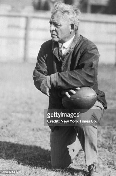 American football coach Amos Alonzo Stagg kneels with a football on his knee. Stagg coached 41 seasons at the University of Chicago and was elected...
