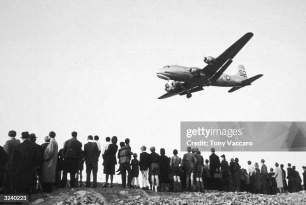 Line of people watch as a supply plane arrives to deliver food and other staples during the Berlin Airlift after World War II, West Germany.