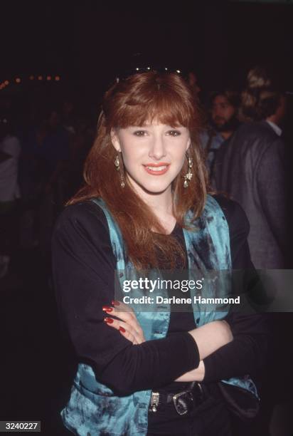 American pop singer Tiffany, wearing a black top and a blue vest, smiling at a party.