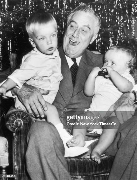 Portrait of U.S. President Franklin Delano Roosevelt holding his grandsons Franklin III and John Bettinger Jr. On his lap at the White house,...