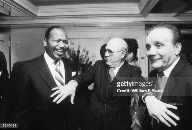 American boxers Sugar Ray Robinson and Jake LaMotta joke as they are separated by one of the guests during Robinson's birthday party at the Carlyle...