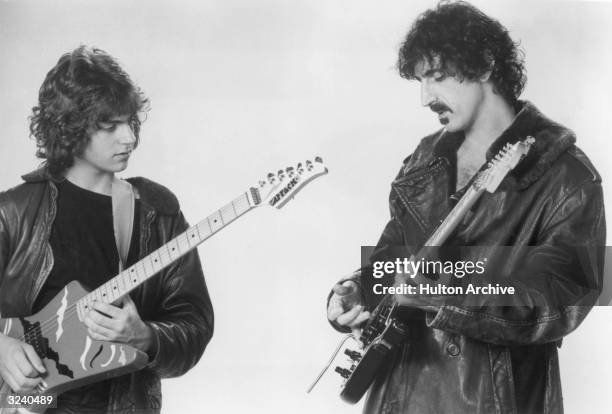 Promotional studio image of American rock guitarist and composer Frank Zappa playing the electric guitar with his son Dweezil Zappa, early.