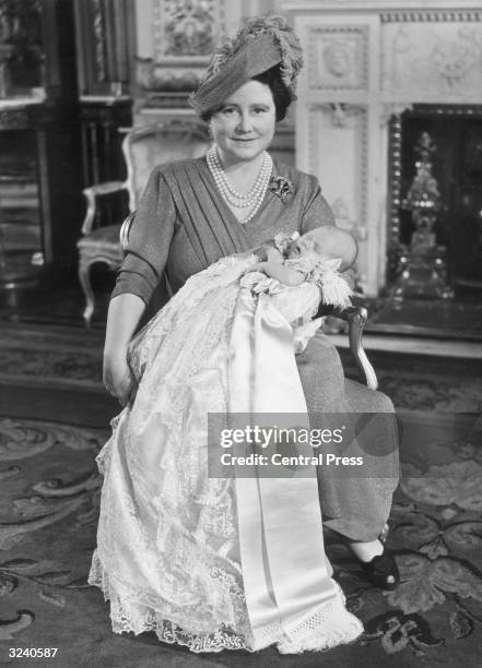 Queen Elizabeth holding Prince Charles, her first grandchild, who is wearing the Royal family christening gown after being baptised at Buckingham...