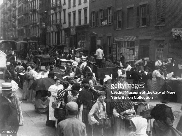 View of crowds of people standing in the street and buying goods from vendors on Hester Street, in the Lower East Side of Manhattan, New York City.