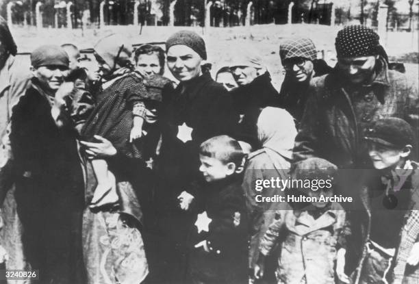 Jewish women and children, some wearing the yellow Star of David patch on their chests, at Auschwitz concentration camp, Poland, undergoing...