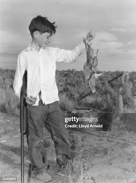 Gregory Hemingway, youngest son of writer Ernest Hemingway, smiles while holding a clutch of dead doves and a gun, Idaho.