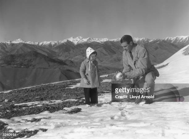 American actor Gary Cooper packs a snowball for his daughter, Maria, on the top of Mount Baldy, Idaho.