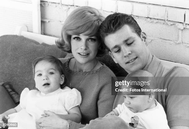 American actor Ryan O'Neal seated with his eight month-old baby son, Griffin, and his wife, actor Joanna Moore, who has their daughter, Tatum, on her...