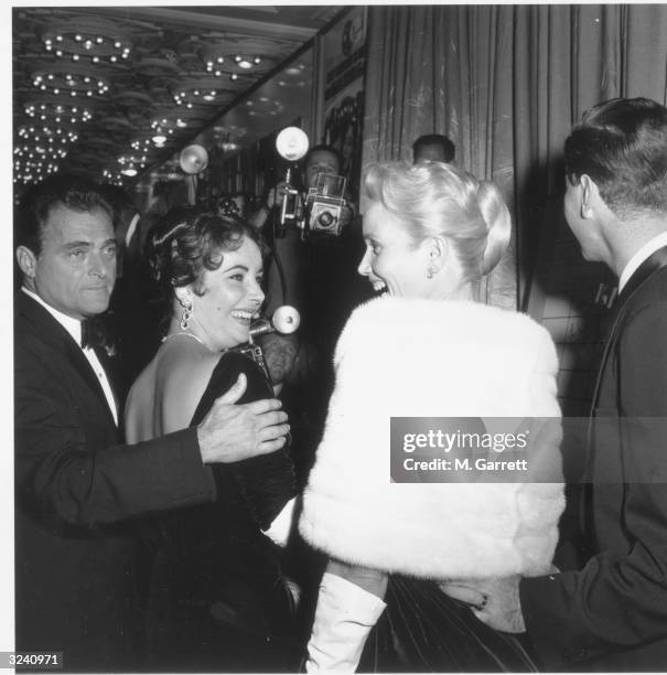 American producer Mike Todd watches as his wife, British-born actor Elizabeth Taylor , and American actor Eva Marie Saint face each other and laugh...