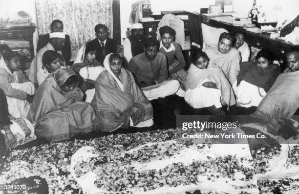 Members of the ashram of Indian political and spiritual leader Mohandas Karamchand Gandhi gather around his body as it lies in the state room in...