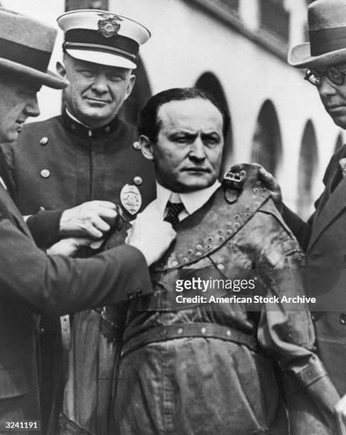 Hungarian-born magician Harry Houdini , aka Ehrich Weiss, is strapped into a leather straight jacket by three men.