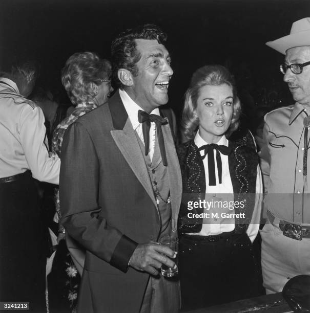 American actor and singer Dean Martin and his wife, Jeanne, stand with singer Sammy Kahn in Western costumes at a SHARE Boomtown benefit at the...
