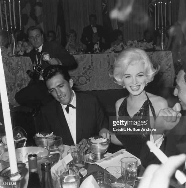 American actor Marilyn Monroe and her date, writer Jose Bolanos , sit at a dining table during the Hollywood Foreign Press Association Awards dinner...
