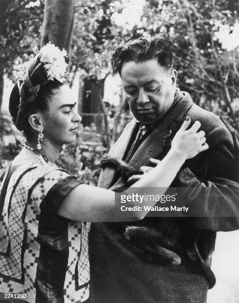 Mexican artist Frida Kahlo pets a monkey, possibly Fulang-Chang, clinging to the jacket of her husband, Mexican artist Diego Rivera .