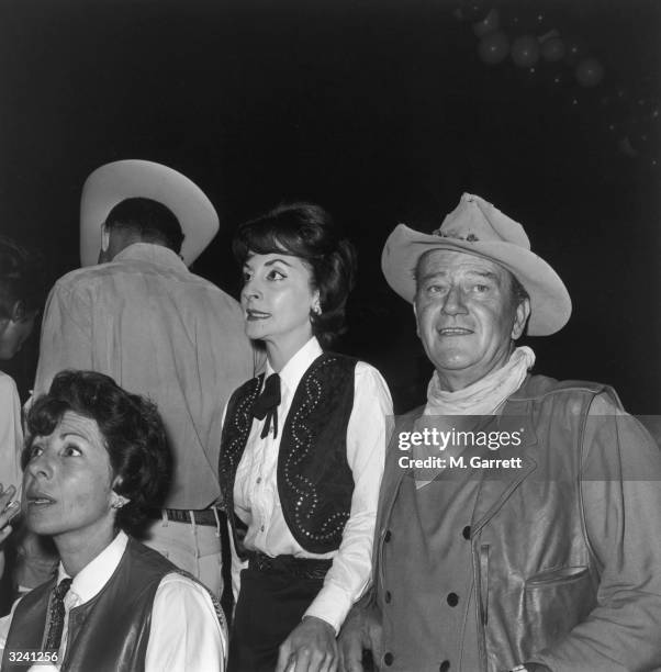 American actor John Wayne and his wife, Pilar, wear Western costumes at a SHARE Boomtown party, Moulin Rouge nightclub, Hollywood, California.