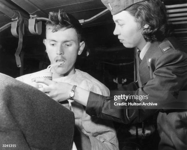 American flight nurse Lieutenant Alice Hendren helps feed freed prisoner of war, Private First Class John L. Robinson aboard a C-124 transport plane...