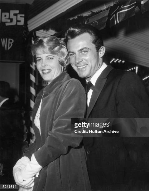 American actor Robert Conrad and his wife, Joan Kenly, stand together and smile outside the Village Theater after the premiere of director Mervyn...