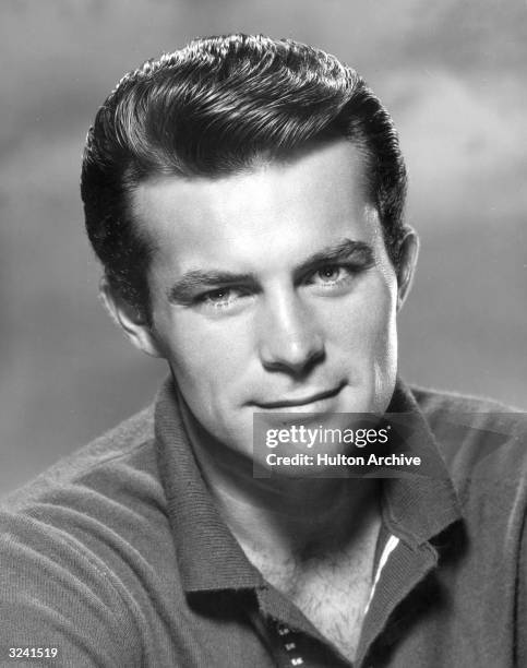 Promotional headshot of American actor Robert Conrad smiling, for the American television series 'Hawaiian Eye'. He is wearing a knit top, unbuttoned...