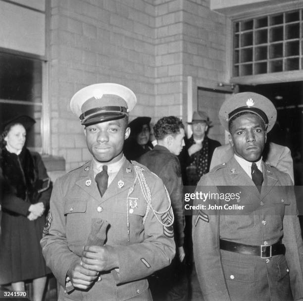 Two African-American soldiers wait for a bus at the Greyhound terminal during Christmas, Washington, DC, World War II.