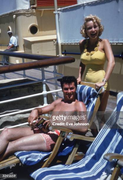 Married American actors Janet Leigh and Tony Curtis, wearing bathing suits, smile aboard the 'Lurline' cruise ship headed for Honolulu, Hawaii.