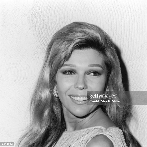 Headshot of American actor and singer Nancy Sinatra, daughter of the American actor and singer Frank Sinatra, smiling over her shoulder and looking...