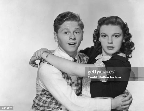 American actors Mickey Rooney and Judy Garland hug and look at the camera with surprised expressions, in a promotional portrait for director George...