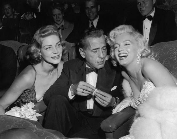 Married American actors Lauren Bacall and Humphrey Bogart pose with American actor Marilyn Monroe at the premiere of director Jean Negulesco's film,...