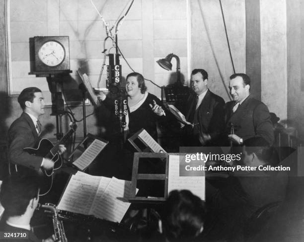 American singer Kate Smith performs with studio musicians on a radio broadcast.