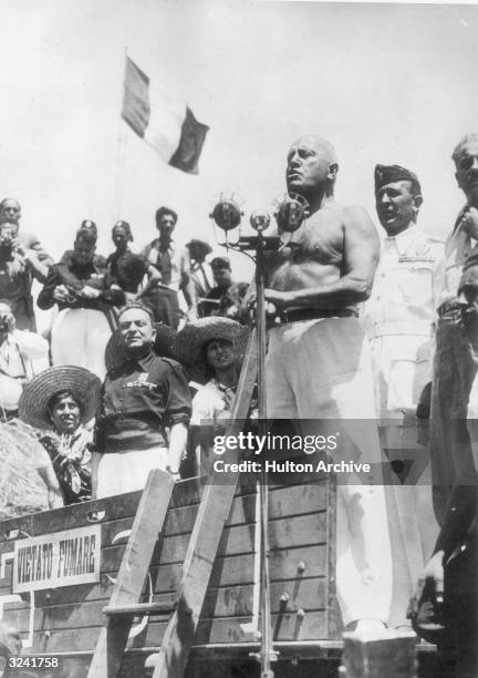 Italian Fascist dictator Benito Mussolini , barechested, speaks from the platform of a threshing machine, Aprilia, Italy. His speech was to...
