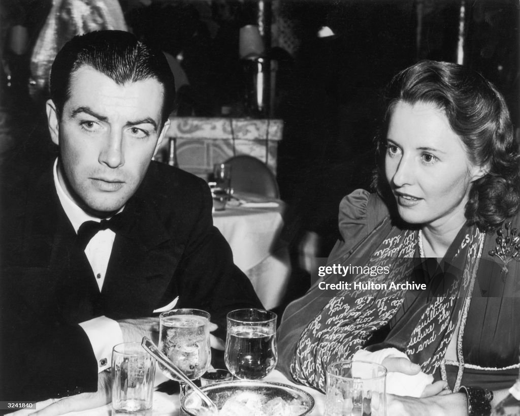 Married American actors Robert Taylor and Barbara Stanwyck sit at a Married American actors Robert Taylor and Barbara Stanwyck sit at a