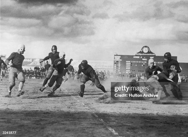 Football players for Boston and Geneva College compete for the ball while running on the field during a game in Boston, Massachusetts. Geneva won the...