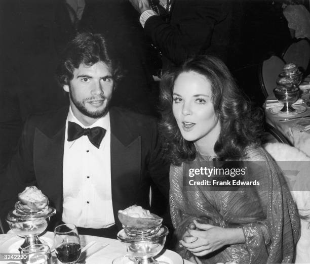 American actor Lorenzo Lamas and his date, American actor Melissa Sue Anderson, of the television show 'Little House on the Prairie,' sit at a table...