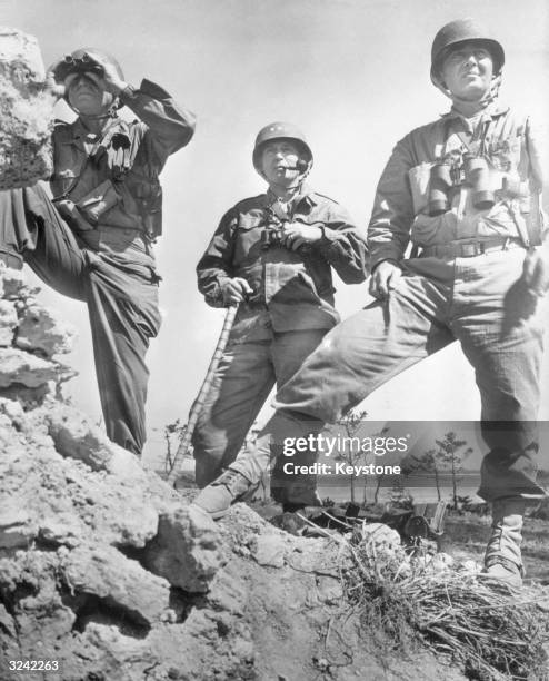 Us generals on a rocky ledge observe American troops advancing towards the town of Naha on the island of Okinawa, in the Ryukyu archipelago, 375...