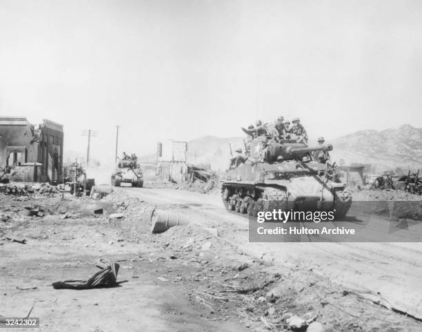 United Nations soldiers sit on top of two UN tanks rumbling through the war-torn main street of Uijongbu after a patrol searching for enemy forces...