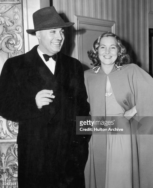 French-born actor Charles Boyer , holding a cigarette, smiling and standing with his wife, British actor Patricia Paterson , posing at a party to...