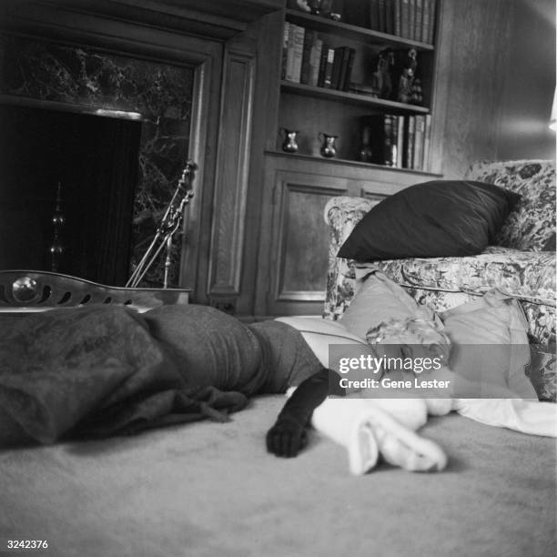 American actor Marilyn Monroe , wearing a lace evening dress and long gloves, lies in front of a fireplace on her fur wrap.