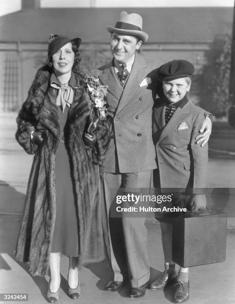 Full-length portrait of American actor Jackie Cooper and his parents, Mr and Mrs Charles Bigelow, standing with their arms around each other and...