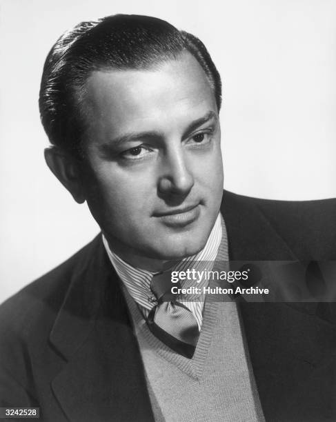 Studio headshot portrait of Canadian-born film director Edward Dmytryk . Dmytryk is wearing a striped shirt with a tie under a V-neck sweater and a...