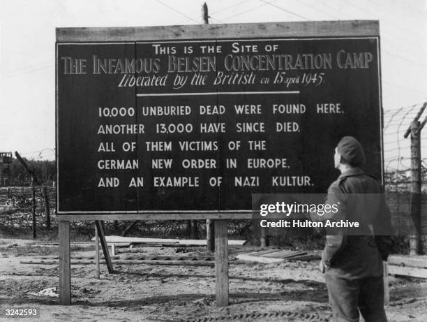 British soldier reads a billboard posted at the entrance of the Belsen concentration camp, Belsen, Germany. After its liberation in April 1945 the...