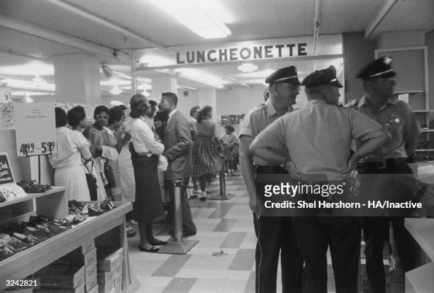 African-American protesters congregate at Brown's Basement Luncheonette during a sit-in while Caucasian police officers observe, Oklahoma.