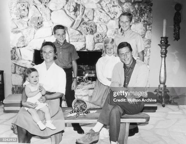 Portrait of American actor and comedian Dick Van Dyke with his wife, Margie Willet, posing in front of a fire place with their four children: Barry,...