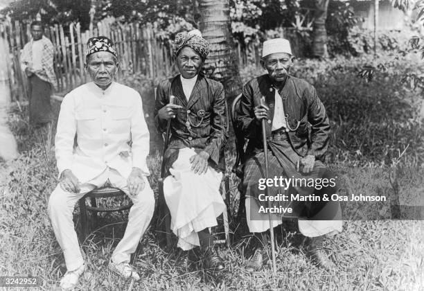 Portrait of three rulers of tribes on the Kinabatangan River, seated outdoors, British North Borneo. Photograph by husband and wife explorers Martin...