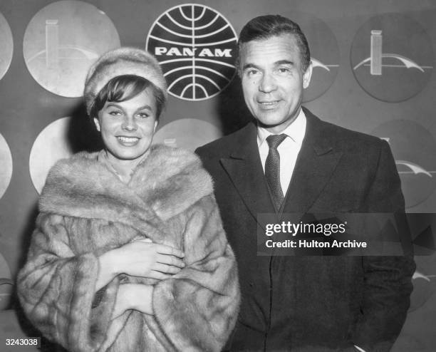 Dominican diplomat Porfirio Rubirosa poses with his wife for the cameras with a Pan-Am Airlines Iogo behind them, New York International Airport, New...