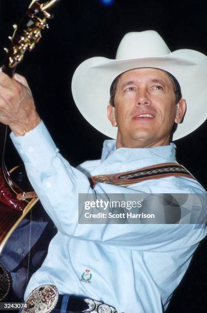 American country musician George Strait, wearing a cowboy hat, playing a guitar during the George Strait Country Music Festival, Sam Boyd Stadium,...