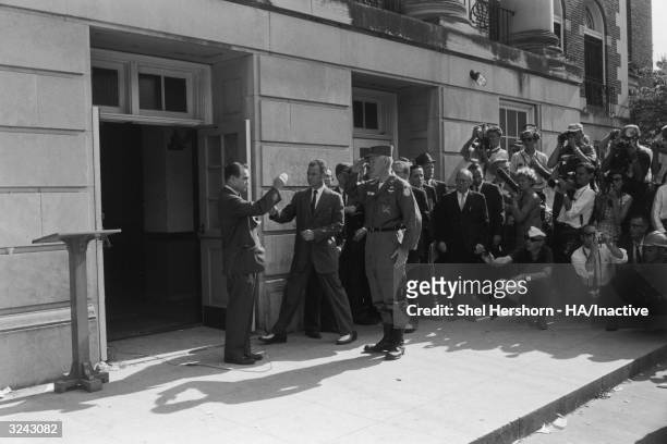 Segregationist Alabama Governor George C Wallace blocks the doorway to the University of Alabama while saluting Brigadier General Henry Graham of the...